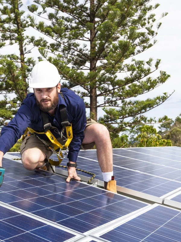 A man is installing the solar panel system on a roof.